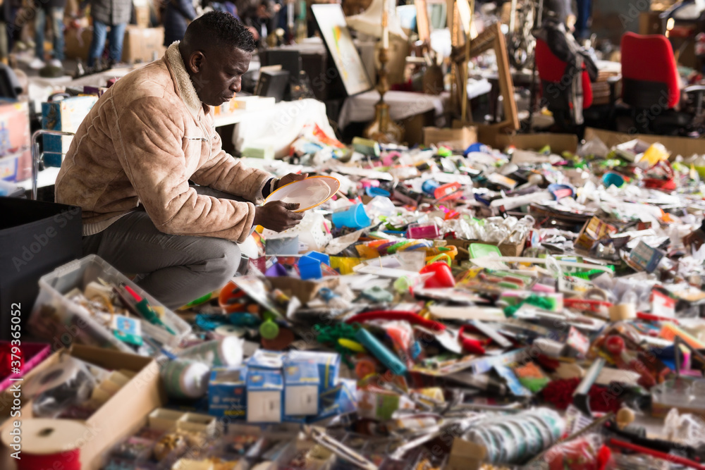 ordinary Afro-American guy considers things sacond hands on flea market