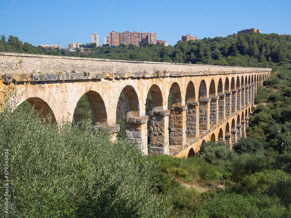 Antique Roman aqueduct known as El Pont del Diable (The devil's bridge) and the apartment buildings on the horizon in Tarragona, Catalonia, Spain.