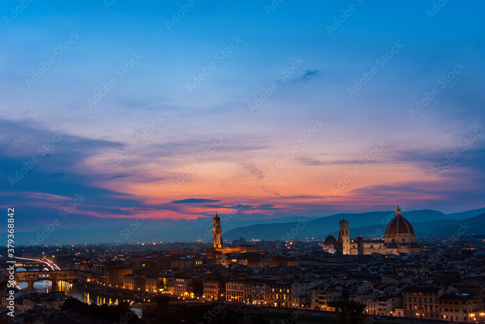 Florence sunset with Lungarno (Arno river bank), the cathedral and Palazzo Vecchio (medieval city hall) illuminated under a pink purple twilight sky