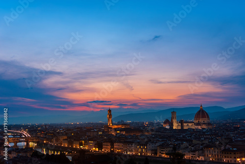 Florence sunset with Lungarno (Arno river bank), the cathedral and Palazzo Vecchio (medieval city hall) illuminated under a pink purple twilight sky