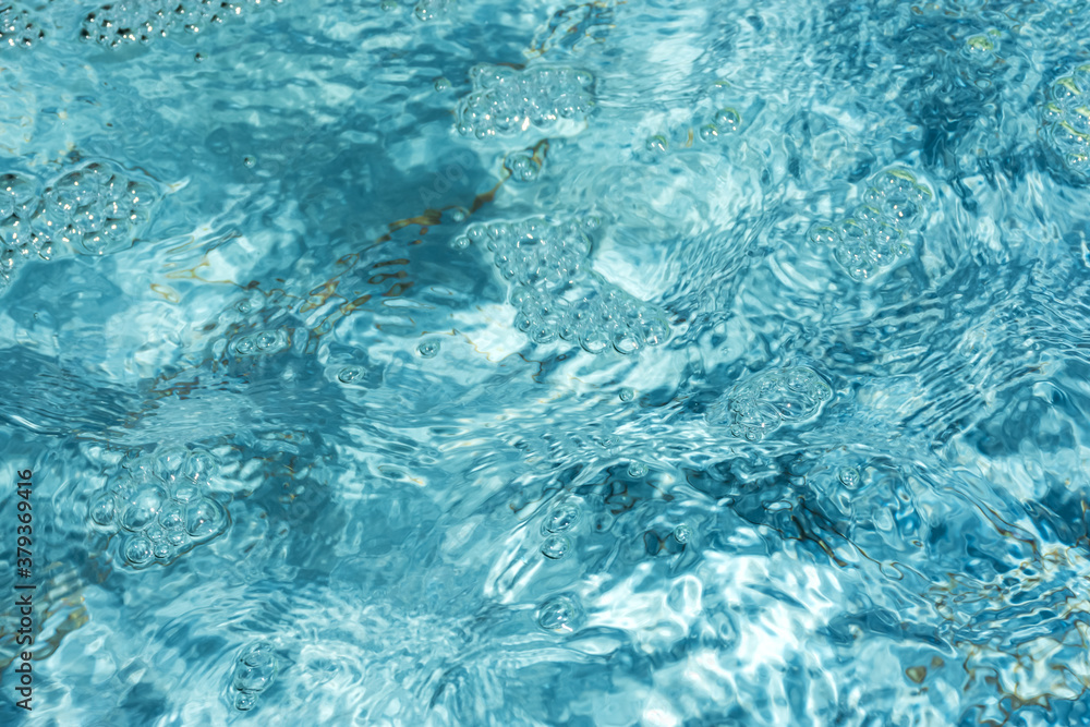 The texture of the pool water. Blue transparent water glows in the sun. Abstract natural background. Full-frame image of the pool. Bright turquoise background.