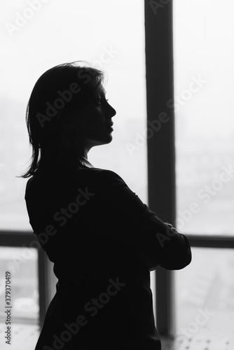 Black and white silhouette of a beautiful young woman at home