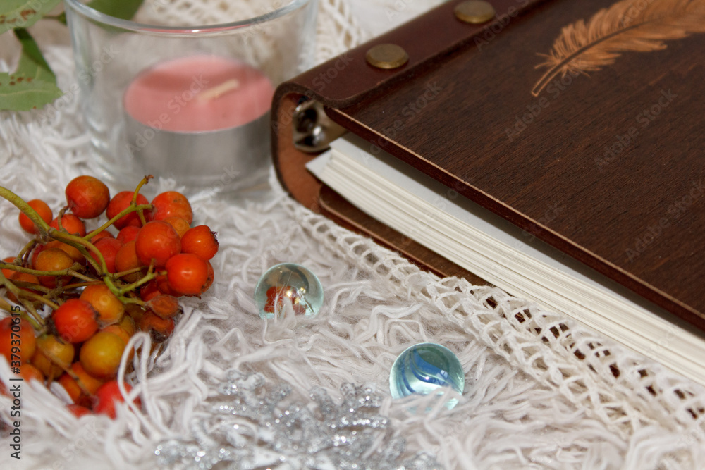 The book lies on soft white fabrics with candles and red branches of mountain ash. Cozy homely atmosphere. Hygge style The book lies on soft white fabrics with candles and red branches of mountain ash. Cozy homely atmosphere. Hygge style