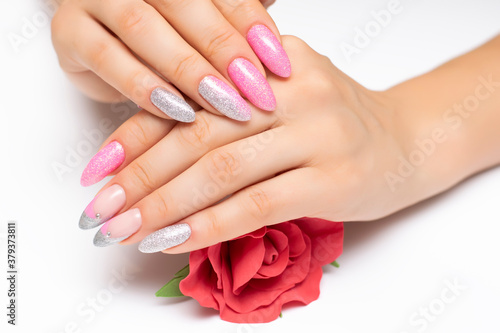 Shiny manicure on sharp long nails with a red rose in the palms. Gel manicure. Pink silver French manicure with crystals.