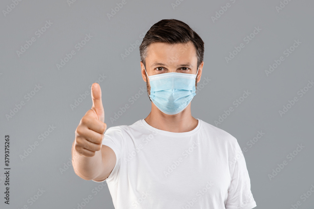 Man in medical protective mask showing thumb up Man in medical protective mask showing thumb up