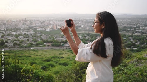 Portrait of Indian female traveler taking video of Bhuj City From Bhujio hills photo