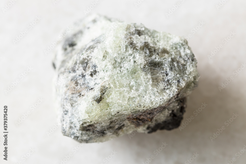 closeup of sample of natural mineral from geological collection - rough saccharoidal Apatite rock on white marble background from Khibiny, Kola Peninsula, Russia closeup of sample of natural mineral from geological collection - rough saccharoidal Apatite rock on white marble background from Khibiny, Kola Peninsula, Russia