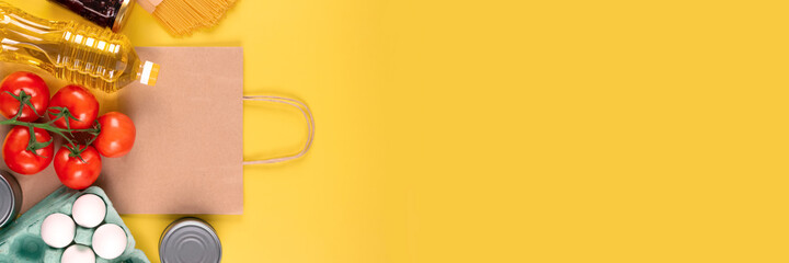 Banner with food donations on yellow background with copyspace - pasta, fresh vegatables, canned food, baguette, eggs, organic oil. Donation, volunteering or contactless delivery food concept. Mockup