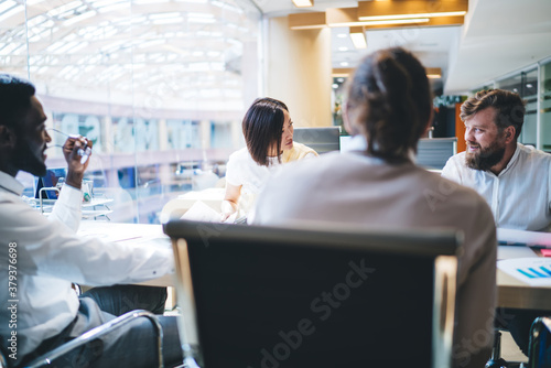 Professional multiracial male and female employees discussing ideas on meeting table planning productive cooperation, crew of diverse business partners communicating and planning working process