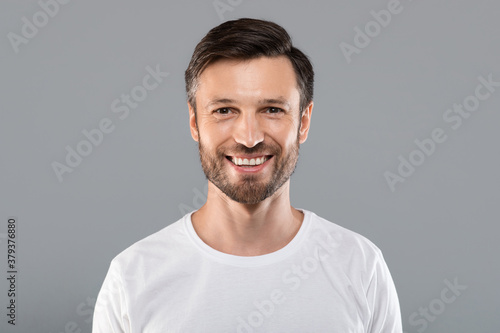 Handsome young caucasian man smiling at camera on grey