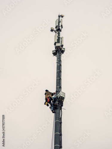 A high-rise worker works on a cell tower