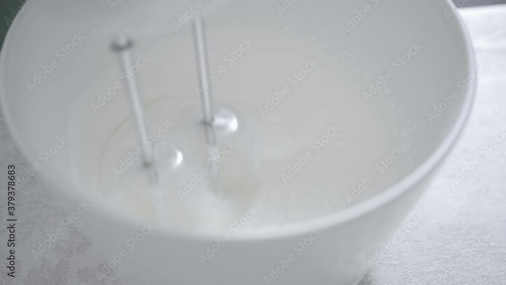 Female chef in gloves mixes white cake cream in a white mold Female chef in gloves mixes white cake cream in a white mold