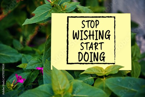 Stop wishing start doing quote written on paper on green garden background. Taking action for achievement in business or life. © Cagkan
