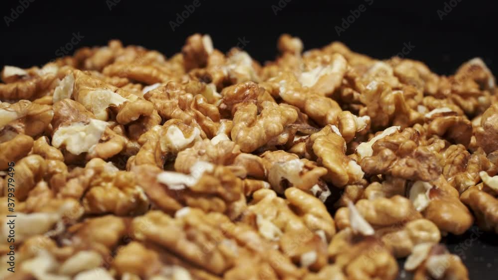 Walnut close up. product rich in minerals and vitamins. Walnut turns in a shot. Walnut kernels rotating and lies under beams of the light. Black background. Walnut close up. product rich in minerals and vitamins. Walnut turns in a shot. Walnut kernels rotating and lies under beams of the light. Black background.