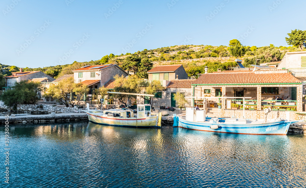 Wooden fishing boats on the pier in the bay of the Adriatic sea near the fishing village in the evening in Lavsa, Croatia