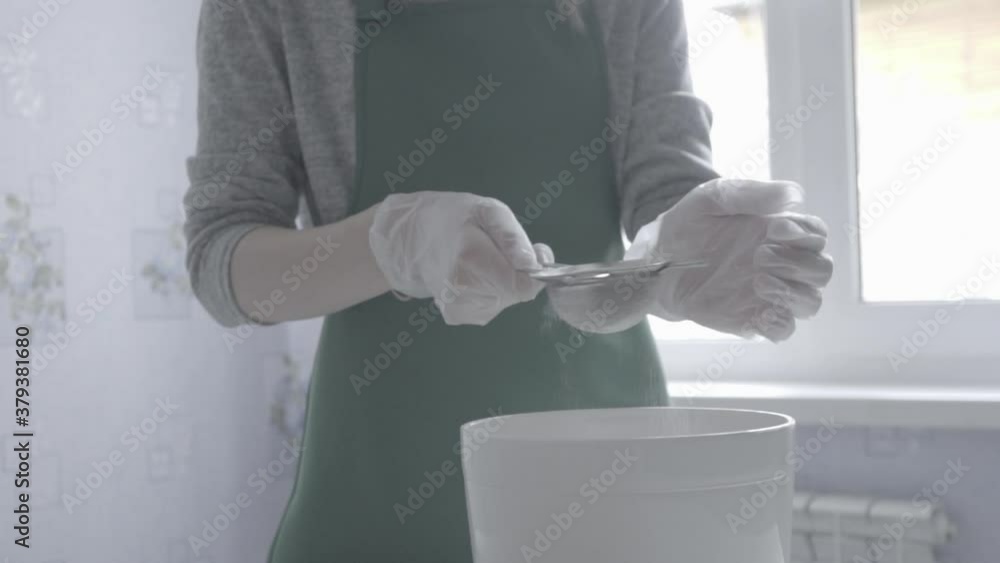 Women's gloved hands pass flour through a sieve. Women's gloved hands pass flour through a sieve.