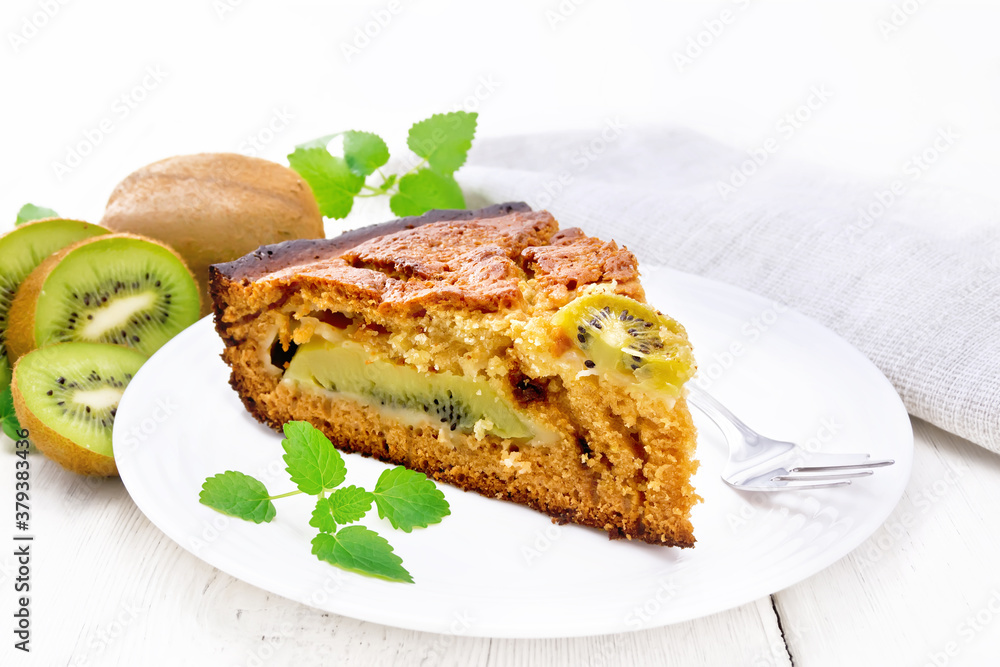 Pie with kiwi in plate on wooden white board Pie with kiwi in plate on wooden white board