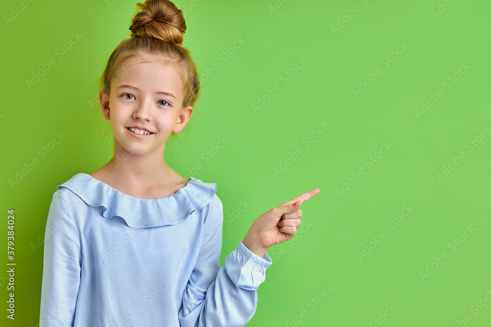adorable caucasian kid girl pointing finger at side, child in blouse smiling, saw something interesting at side adorable caucasian kid girl pointing finger at side, child in blouse smiling, saw something interesting at side