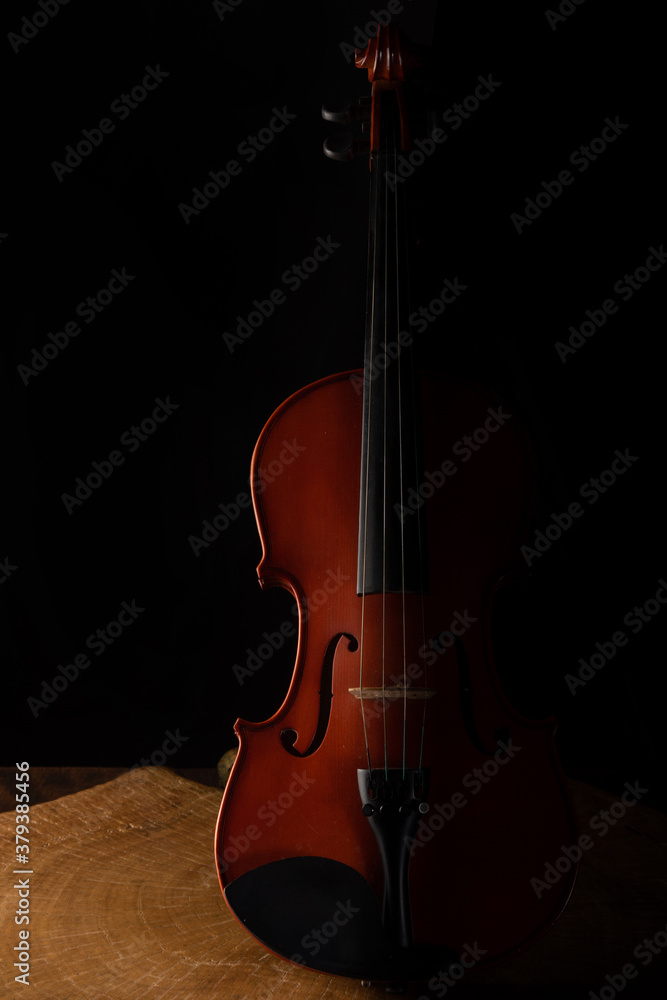 Old and beautiful violin on a rustic wooden surface and black background low key portrait, selective focus. Old and beautiful violin on a rustic wooden surface and black background low key portrait, selective focus.