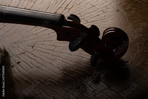 Foto Details of an old and beautiful violin on a rustic wooden surface and black background, low key portrait, selective focus