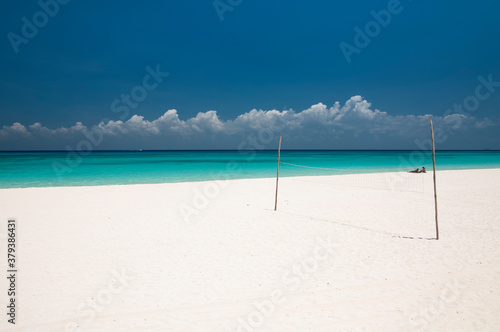 Fototapeta Naklejka Na Ścianę i Meble -  Caribbean white beach with a volleyball net, in the background a couple of tourists and the turquoise sea. ideal place to relax in contact with nature in Tulum, Mexico