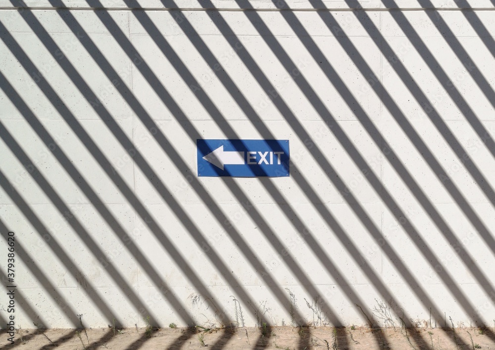 Fototapeta premium Segnale di uscita su uno sfondo murale e texture di ombre a strisce