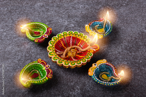 Top view overhead clay lit light a fire already on Diya or oil lamp, studio shot on concrete background, Decoration of Hinduism rangoli, Happy celebration Deepavali or Diwali festival concept