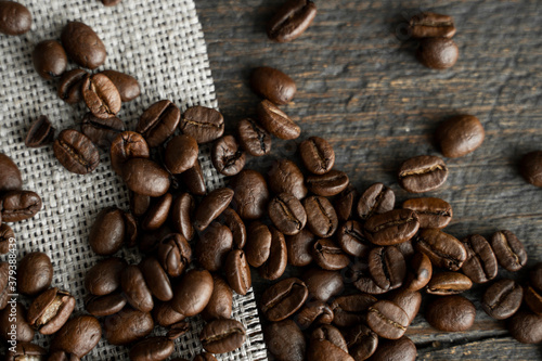 Coffee beans on a linen textile and on a wooden table background. Fresh arabica coffee beans.
