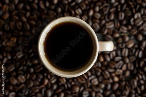 Cup of coffee with roasted coffee beans background. Mug of black coffee.