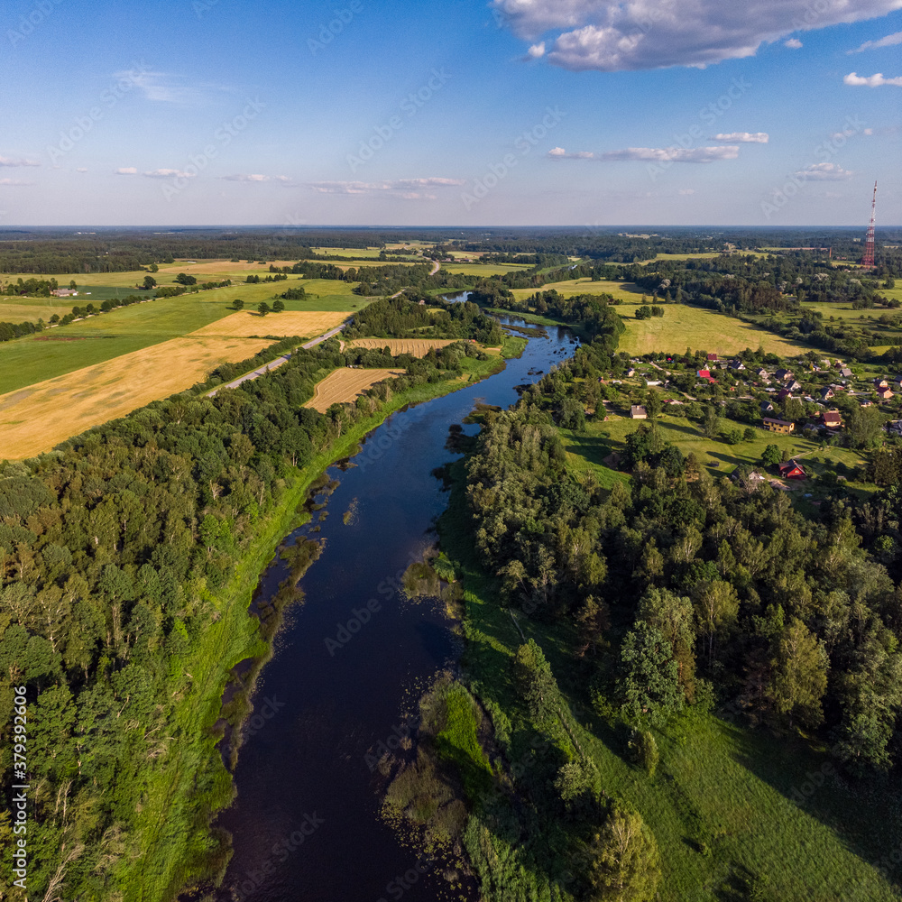 Areal countryside view o river Venta flowing through lovely environment with trees on a warm summer day.