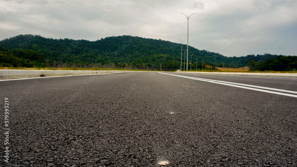 low angle shot of asphalt road and mountain in background in Malaysia low angle shot of asphalt road and mountain in background in Malaysia