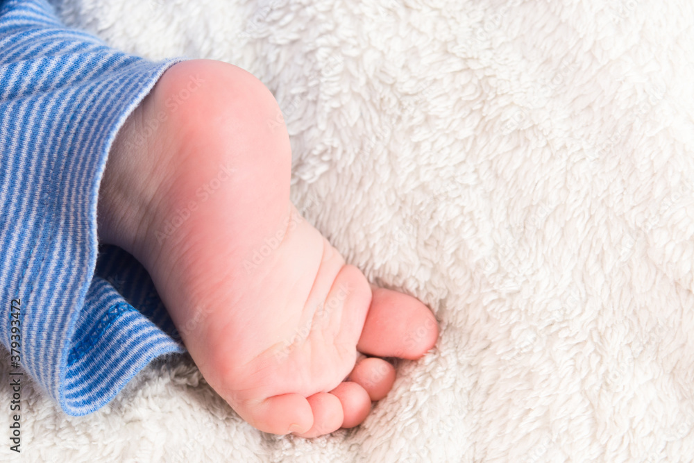 Caucasian human baby little sweet foot on soft white plaid. Sleeping kid. One leg. Copy space Caucasian human baby little sweet foot on soft white plaid. Sleeping kid. One leg. Copy space