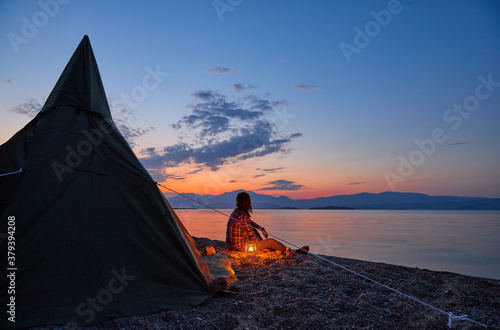 Man relaxes on the beach at the sunset at the camp