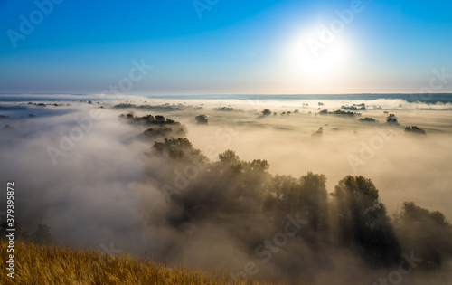 Morning foggy valley with river, hills and withered grass photo