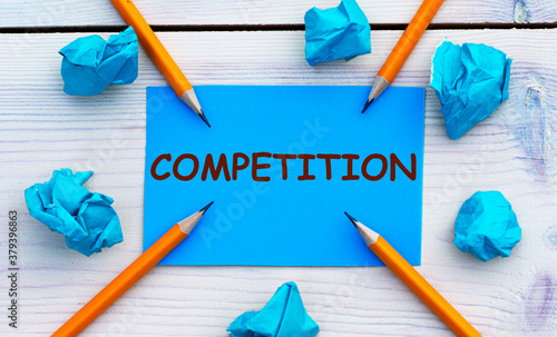 COMPETITION - word on blue paper on a light background with crumpled pieces of paper and pencils photo