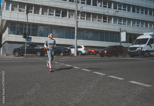 A young woman running on a crosswalk © Taras Grebinets