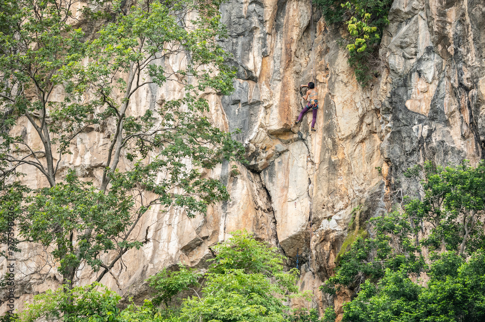 Strong Asian woman training and climbing cliff in nature, Thailand.