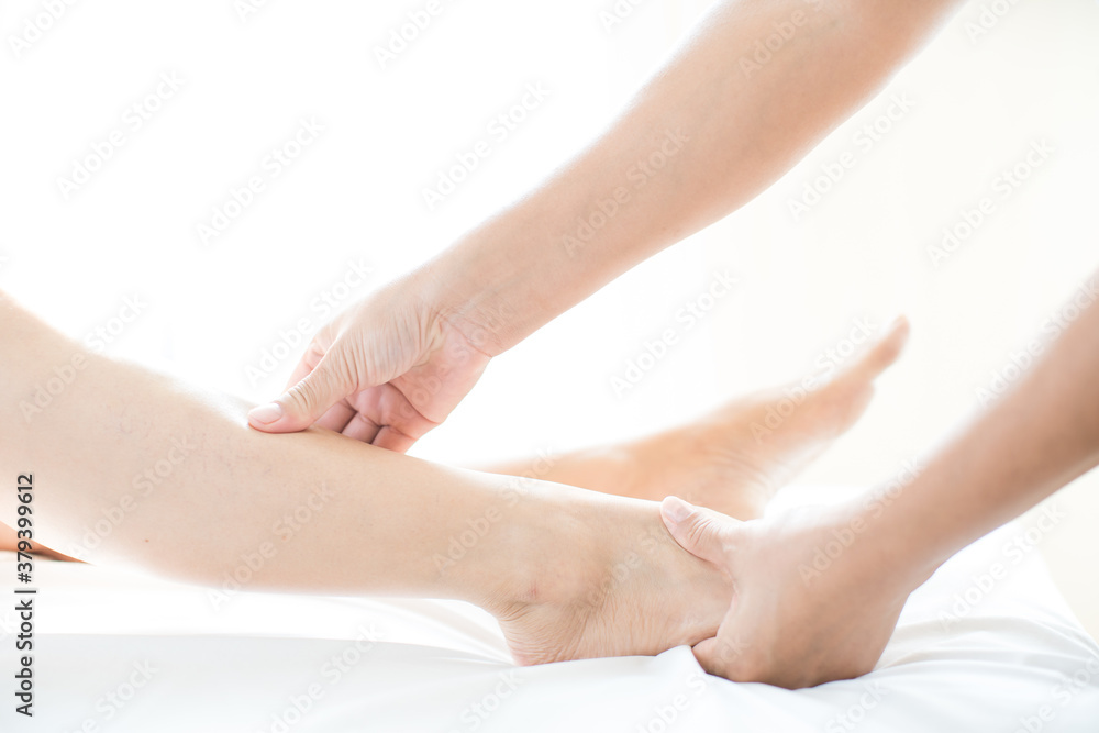 Young woman doing foot massage in spa massage. Foot massage. Close up of hands therapist's massaging female foot.