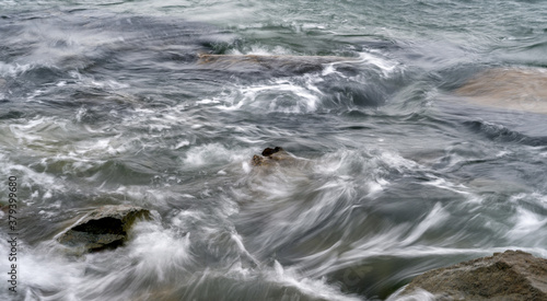 Waves at the seashore or pier aptured with a slow shutter speed. Natural abstract motion background.