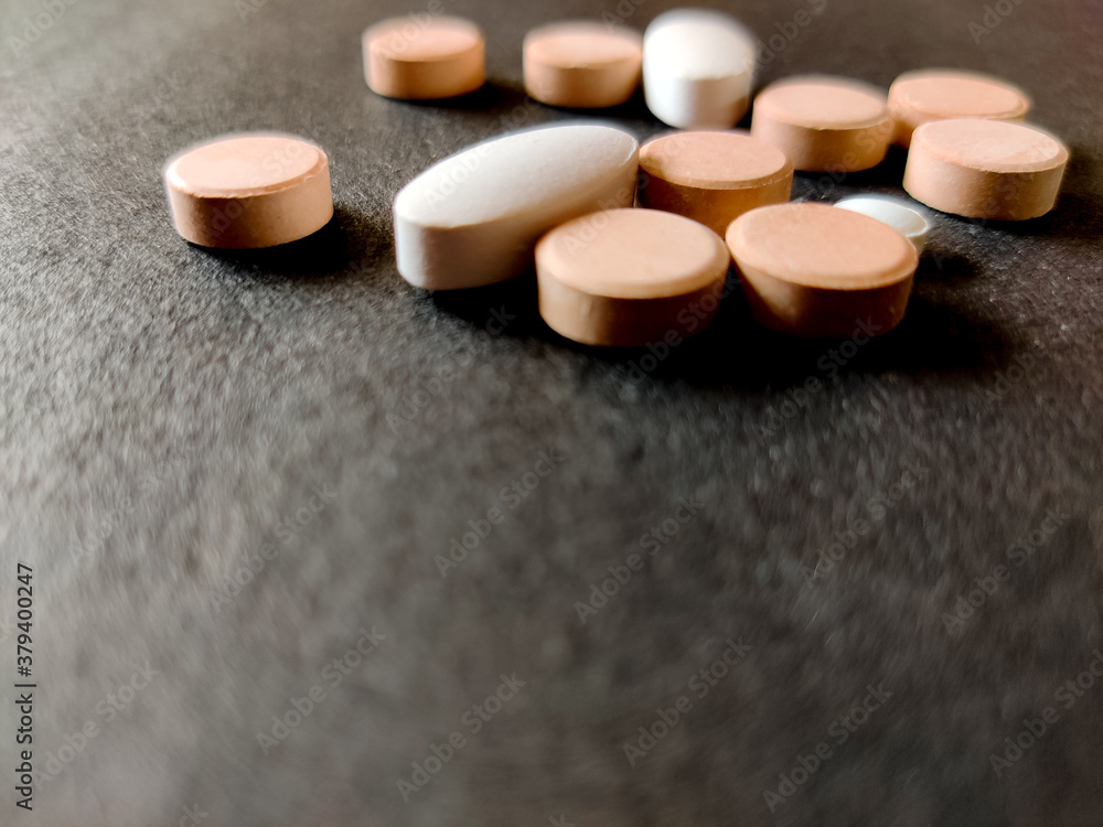 Concept of tablets.Covid-19 corona virus cure.White and orange color medical pills on black background. Concept of tablets.Covid-19 corona virus cure.White and orange color medical pills on black background.