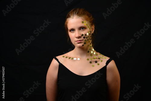Beautiful young woman face close up portrait in studio on black. various emotions. foil stars glued to the face