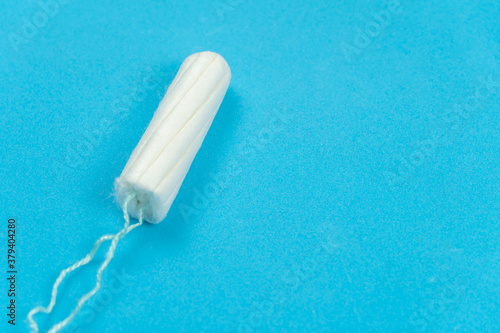 Medical female tampon on a blue background with copy space. Hygienic white tampon for women. Menstruation, a means of protection.
