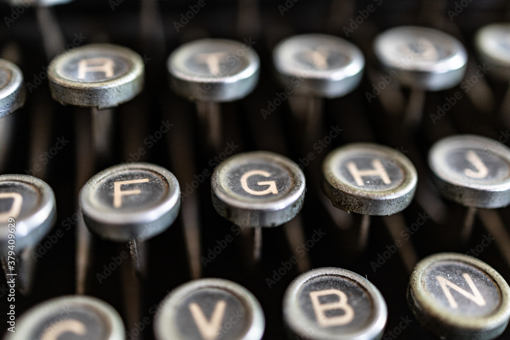 Selective focus close up on the keys of a black, vintage typewriter of the past century. Focus on F and G letters, blurred background. Selective focus close up on the keys of a black, vintage typewriter of the past century. Focus on F and G letters, blurred background.