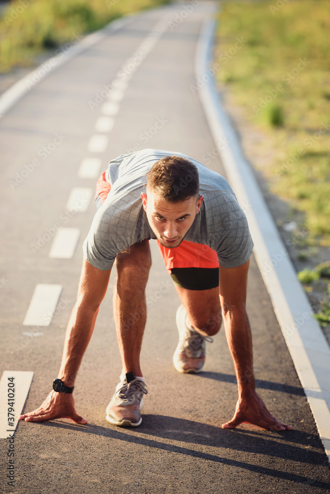 Sports man runner with smart watch in start position preparing to run Sports man runner with smart watch in start position preparing to run