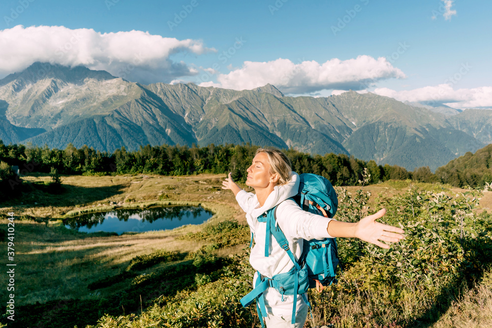 Happy woman hiker spread her arms out of the pleasure of success in the mountains.