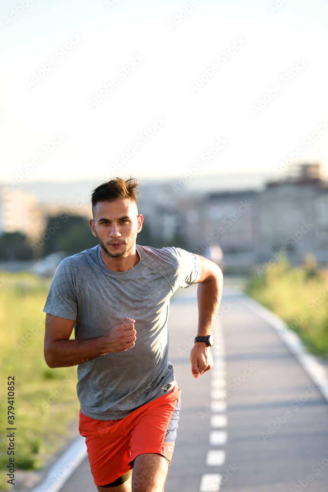 Fototapeta premium Sports man running fast outdoors on a race track