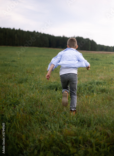 Little boy runs through a green field