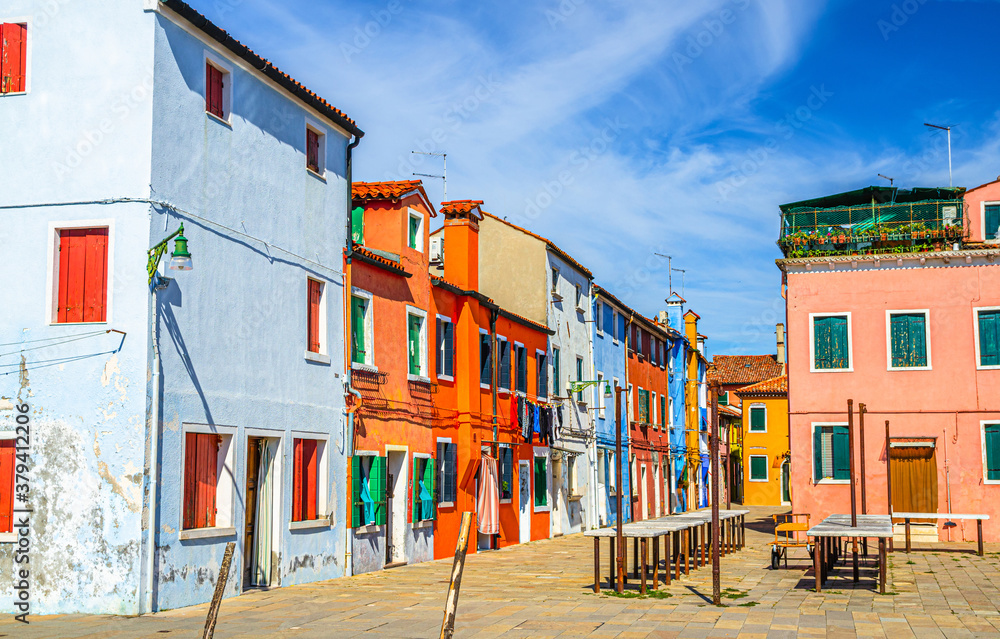 Colorful houses of Burano island. Multicolored buildings in narrow street, blue sky background in sunny summer day, Venice Province, Veneto Region, Northern Italy. Burano postcard