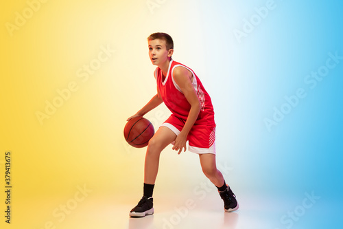 Strategy. Full length portrait of young basketball player in uniform on gradient studio background. Teenager confident posing with ball. Concept of sport, movement, healthy lifestyle, ad, action © master1305