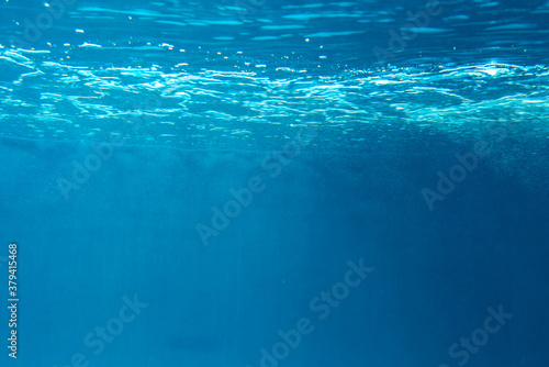 Summer. Texture of water surface. Underwater background. Waves effects. Blue underworld. Ocean, sea. Diving. Blue sea pool water. Bottom view.